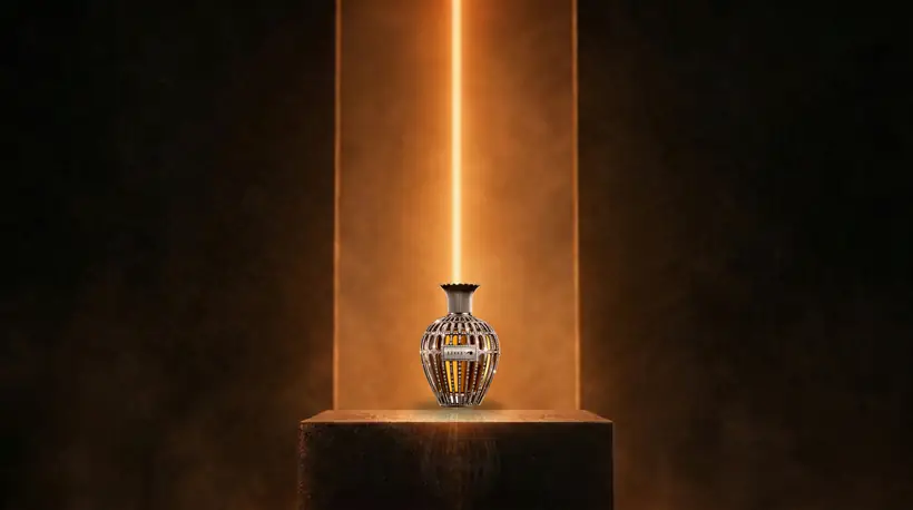 The flacon close up in front of the glowing orange slit, its crystals catching the light, the top of the plinth in the foreground